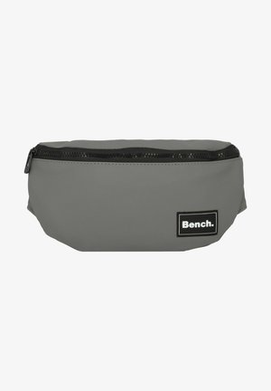 Sac banane en tissu gris avec fermeture éclair noire et patch logo de la marque Bench sur le devant côté droit.