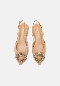 Bežīgas zamša slingback kurpes ar norādītu purngalu un dekoratīvu apaļu rhinestone apdari. Iespējas ar zemiem papēžiem un regulējamu siksniņu.