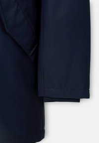 Giacca blu navy con una texture liscia, dotata di un colletto appuntito e maniche piegate. Il tessuto sembra resistente con una finitura elegante.