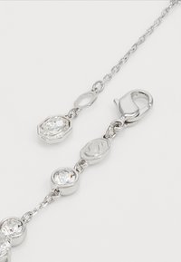 Silver bracelet with round and hexagonal clear crystals, linked by small chains and featuring a lobster clasp closure.