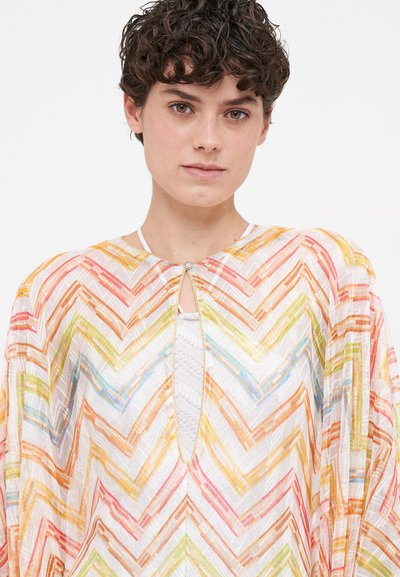 Poncho transparent, multicolor, cu un model în zigzag în nuanțe de portocaliu, roz, verde și albastru. Dispune de un guler rotund și un detaliu în formă de cheiță în față.