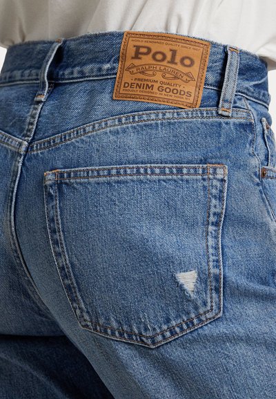 Ljusblå denimjeans med en blekt textur. Har en läderetikett från "Polo Ralph Lauren" på midjan och bakfickorna med en fransad detalj.