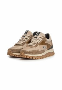 Zapatillas beige con materiales de ante y lisos, que cuentan con un acento marrón texturizado, una mediasuela blanca y una suela exterior de goma marrón resistente.