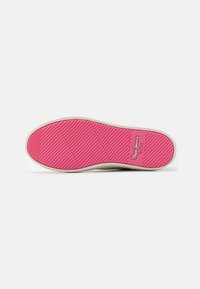 Fodtøjssål med tekstureret pink gummi, der har diagonale riller og en hvid kant. Branding synlig i hjørnet.