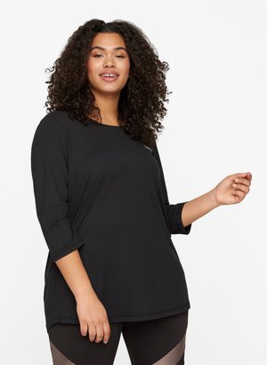 Black, long-sleeve top with a round neck, relaxed fit, and soft texture. Features subtle stitching accents, worn with dark leggings.