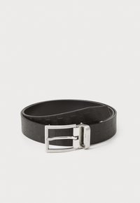 Cinturón de cuero negro con un patrón texturizado en forma de chevron, rematado con una hebilla de metal plateada y brillante. Forro interior suave.