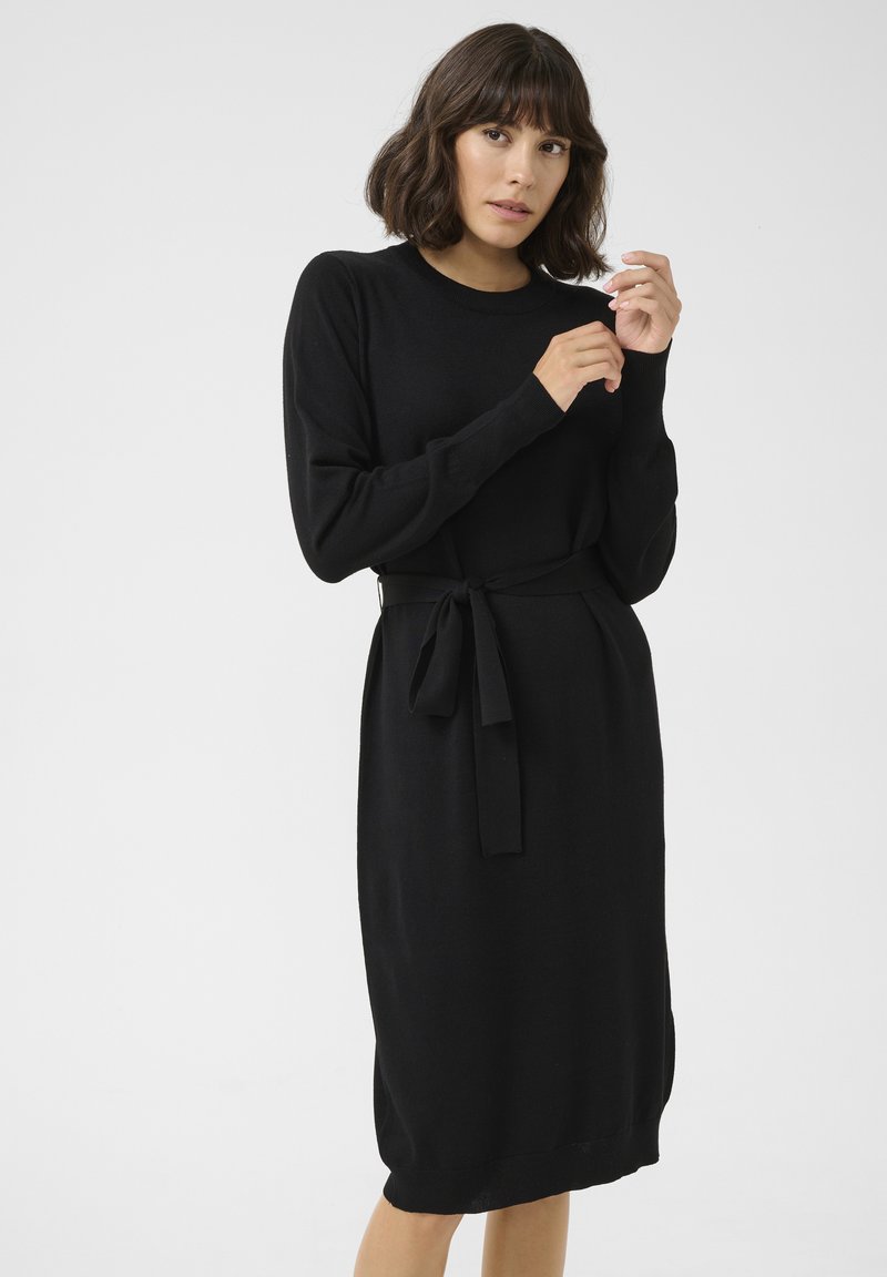 Schwarzes Strickkleid mit langen Ärmeln, einem runden Ausschnitt und einer taillierten Taille. Es hat ein elegantes, strukturiertes Finish und fällt bis zur Mitte der Waden.