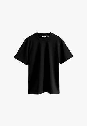 Camiseta negra de manga corta hecha de una suave tela de algodón. Presenta un cuello redondo y un corte holgado sin patrones ni acentos visibles.
