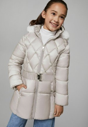 Cappotto invernale imbottito di un beige chiaro con trapuntatura a rombi, cappuccio in pelliccia sintetica, zip frontale e dettaglio della cintura. Presenta tasche laterali e accenti decorativi.