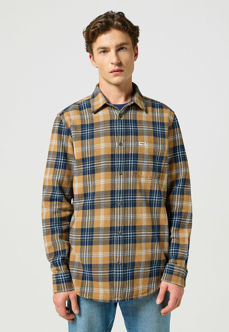 Flanellskjorta i brunt, marinblått och vitt rutmönster. Har en knäppbar krage, långa ärmar och en bröstficka. Texturerad tyg.