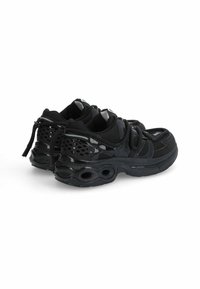 Czarne buty sportowe z siateczkową cholewką, błyszczącymi akcentami i teksturowaną podeszwą z okrągłymi wycięciami zapewniającymi wentylację i amortyzację.