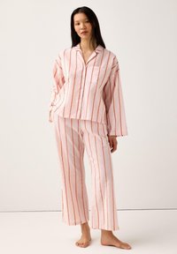 Randig pyjamaset i ljusrosa och orange. Toppen har knäppning med knappar och en ficka; byxorna har en avslappnad passform och raka ben.