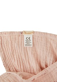 Light pink fabric with a textured surface, featuring a sewn tag with brand name and care instructions, folded to show detail.