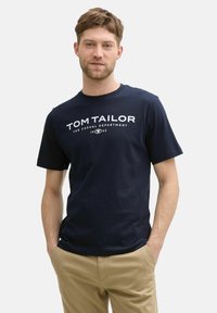 Navyblaue Baumwoll-T-Shirt mit weißem Text "TOM TAILOR" und Logo auf der Vorderseite, Rundhalsausschnitt und kurzen Ärmeln. Weiches, lässiges Design.