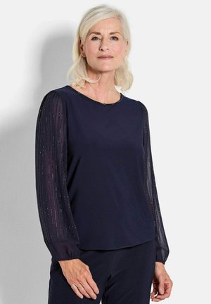 Navy-Oberteil mit undurchsichtigem Körper und transparenten, plissierten Ärmeln mit metallic Akzenten. Runder Ausschnitt, glatte Textur und elegantes Design.