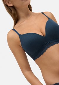 Bralette de canalé en color navy con terminaciones de encaje en la parte inferior. Cuenta con tirantes finos ajustables y un diseño de escote pronunciado.