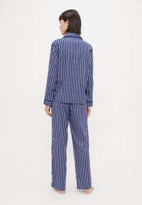 Námornícky a biely pruhovaný bavlnený pyžamový set s dlhými rukávmi, gombíkovou košeľou a voľnými nohavicami, s náprsním vreckom a manžetami na rukávoch.