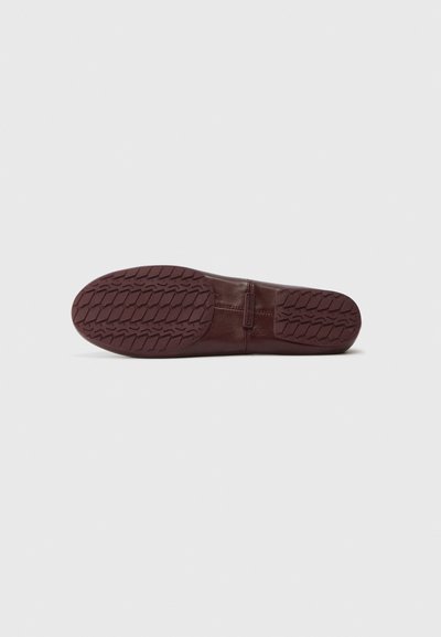 Brown leather shoe sole with a textured tread pattern, featuring a smooth finish and minimal detailing near the heel.