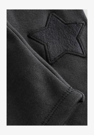 Tessuto di felpa nero con un grande patch a stella nera dal finish testurizzato simile al feltro, posizionato sulla manica.