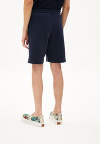 Navyblauwe shorts met een elastische tailleband, met een gladde textuur. Gecombineerd met gestreepte instappers in tropische kleuren.