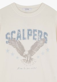 Creme sweatshirt med "SCALPERS" i blåt distressed skrift, en ørner grafisk illustration med udfoldede vinger, samt lyseblå stjerne detaljer.