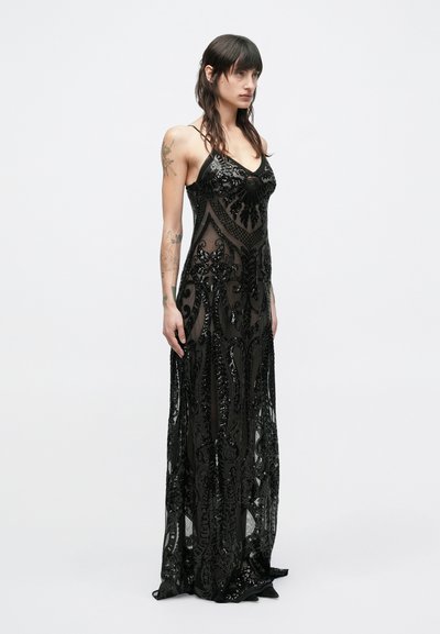 Mustast litritega kaunistatud pidulik kleit keeruka helmestöö ja läbipaistva kangaga, millel on vormitud ülakeha, õhukesed rihmad ja voolav seelik.