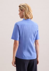 Camicia blu a maniche corte realizzata in tessuto liscio, con colletto classico e vestibilità su misura, dal design posteriore pulito e dettagli minimali.