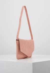 Różowa torebka na ramię z klapką, prostym paskiem, prostokątnym kształtem i teksturowaną powierzchnią. Minimalistyczny design bez widocznych elementów metalowych.