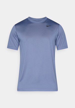 Cămașă sport cu mânecă scurtă, de culoare albastru deschis, cu un guler în degrade de albastru închis, logo-ul Nike în negru pe pieptul stâng, textură netedă.