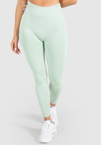 Mátově zelené legíny s vysokým pasem vyrobené z elastické tkaniny. Mají žebrovanou texturu a bezešvý design pro pohodlí a lichotivý střih.