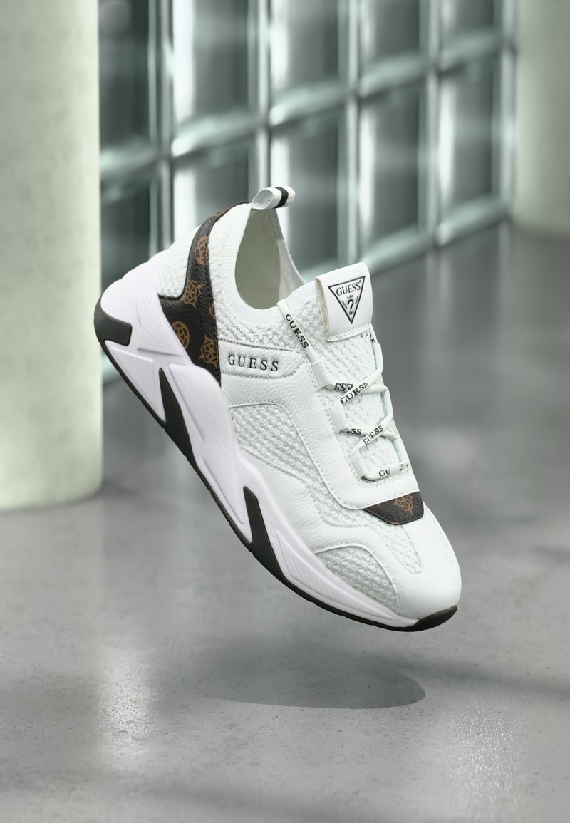 Bela športna superga z mrežastimi in usnjenimi materiali, s črnim in rjavim vzorčastim poudarkom na peti ter teksturiranim podplatom. Logotip na jezičku.