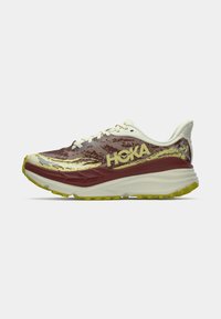 HOKA skriešanas apavi bordo, krēmkrāsā un dzeltenā krāsā. Iespējas: sieta augšdaļa, mīkstināta starpzole un teksturēts zole saķerei.