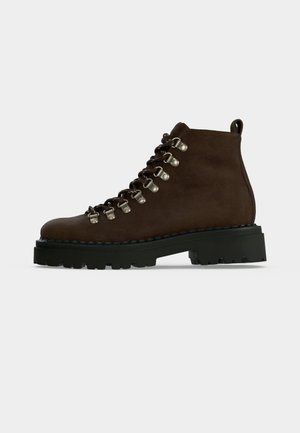 Dark brown leather hiking boot with silver metal eyelets, black thick treaded sole, and pull tab at the heel, shown in side profile.