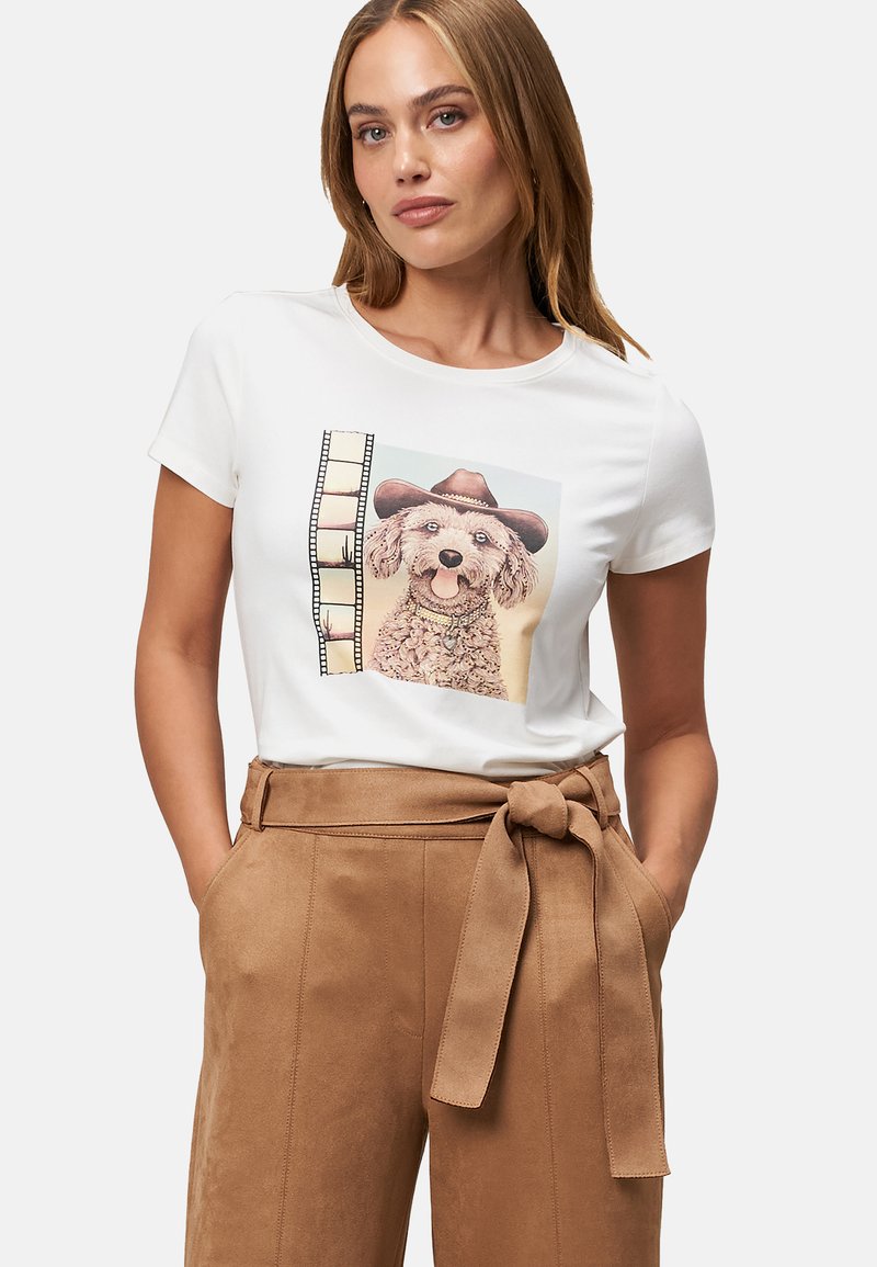 White short-sleeve t-shirt featuring a graphic of a dog in a brown cowboy hat, paired with tan high-waisted trousers with a tie belt.