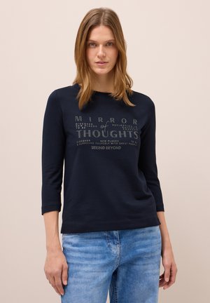 T-shirt à manches longues bleu marine avec un design graphique texturé et des lettres blanches. Tissu doux et extensible avec une coupe décontractée.