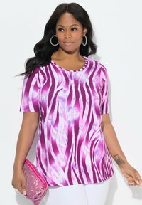 Camiseta de rayas púrpura y blanca con mangas cortas, cuello redondo y una textura suave. Combinada con un bolso de mano rosa adornado.