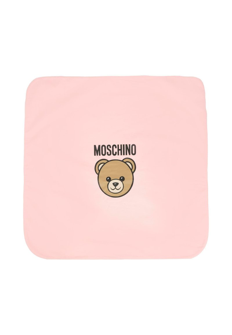 Vaaleanpunainen peitto, jossa on sarjakuvamaisen karhun kasvot ja sana "MOSCHINO" painettuna ylös paksulla mustalla tekstillä. Tasainen, pehmeä kangas. Neliön muotoinen.