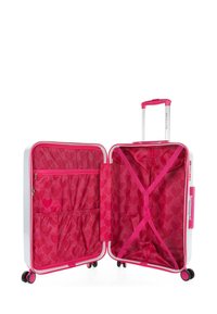 Maleta rígida con un exterior blanco, acentos en rosa brillante y un interior forrado con tela de patrón rosa. Sus características incluyen un asa telescópica y cuatro ruedas.