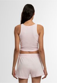 Lichtroze cropped tanktop met geribbeld textuur, gecombineerd met bijpassende lichtroze shorts met een elastische tailleband en een ontspannen pasvorm.