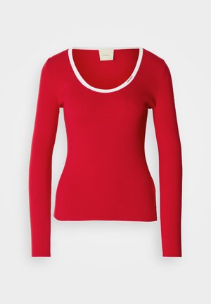 Piros, hosszú ujjú felső bordás anyagból, kerek kivágással, fehér díszítéssel a nyakrész körül. Szoros fazonú.