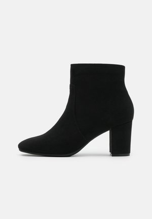 Bottines en suède noir avec un bout pointu et un talon carré. Le design présente un dessus sans couture et une texture lisse.