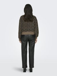 Brun og sort mønstret cropped sweater med tekstureret overflade, parret med højtaljede sorte læderbukser og sorte sneakers.