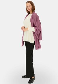 Lekki, miękki fioletowy szal zarzucony na kremowy sweter, w połączeniu z czarnymi spodniami i czarnymi butami. Prosty wzór z frędzlami na szalu.