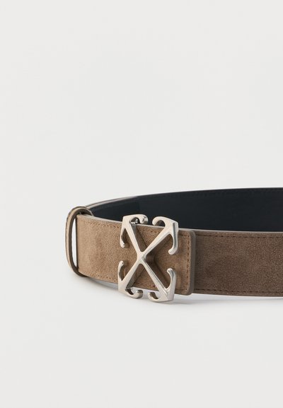 Ζώνη από ταφ δέρμα σουέντ με μεγάλη ασημένια μεταλλική αγκράφα που διαθέτει συμμετρικό σχέδιο σε σχήμα σταυρού, σε λευκό φόντο.