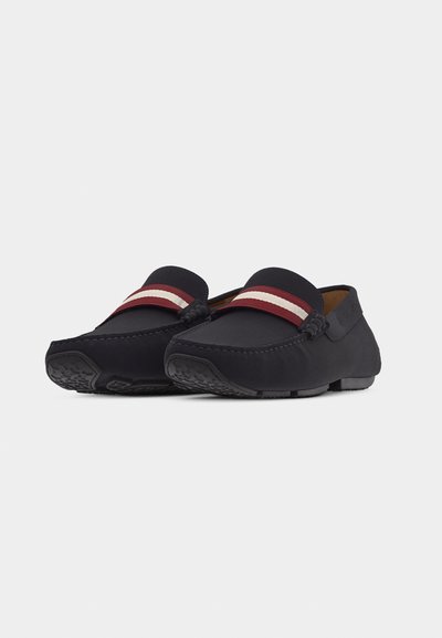 Mocassins noirs avec une bande rouge et blanche rayée sur le dessus, semelles en caoutchouc texturées et détails cousus le long de l'avant du pied.