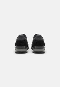 Scarpe da ginnastica nere con tomaia in suede e sintetico, accenti grigi, colletto imbottito e suola con grip testurizzato. Due stufi posteriori per la ventilazione.
