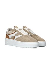 Beige suède sneakers met witte leren accenten en een bruine hak, voorzien van platte witte veters en een gevoerde tong, op een witte rubberen zool.