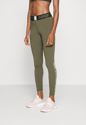 Legginsy w kolorze oliwkowej zieleni od Nike z czarnym pasem i białym logo po boku, charakteryzujące się gładkim, elastycznym materiałem oraz dopasowanym krojem.