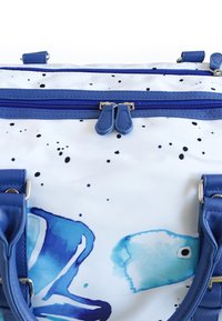 Eine blau-weiße Tasche mit glänzender Oberfläche, die abstrakte Fischmuster zeigt, zwei blaue Reißverschlüsse und robuste blaue Griffe hat.