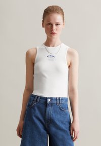 Witte geribde tanktop met een ronde halslijn, met blauwe tekst en een grafische print. Gecombineerd met hoge, blauwe denim shorts.